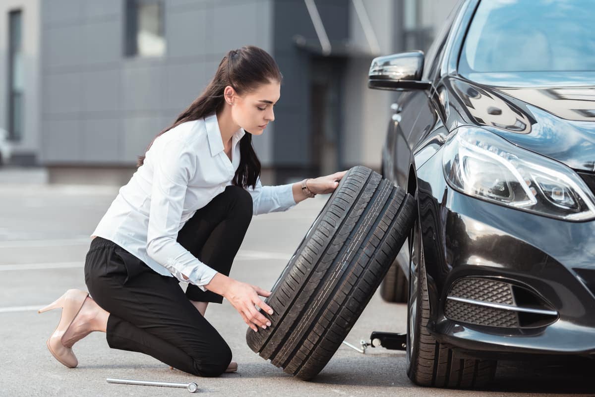Woman relplacing tire on car